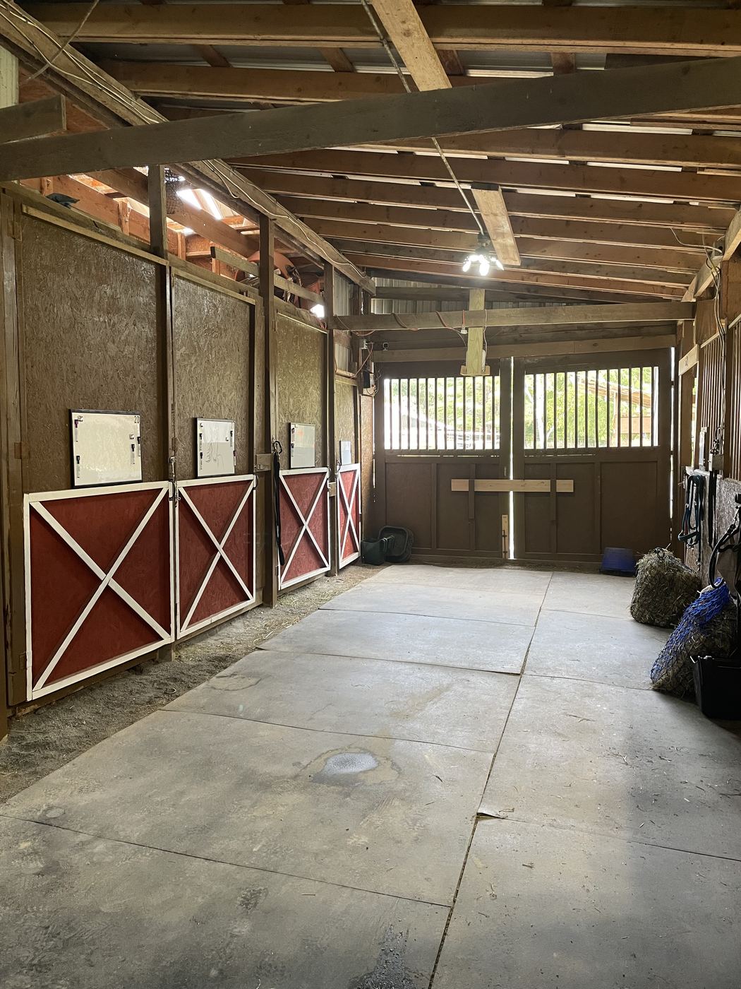 A row of red and white cross-buck stall doors with feed charts